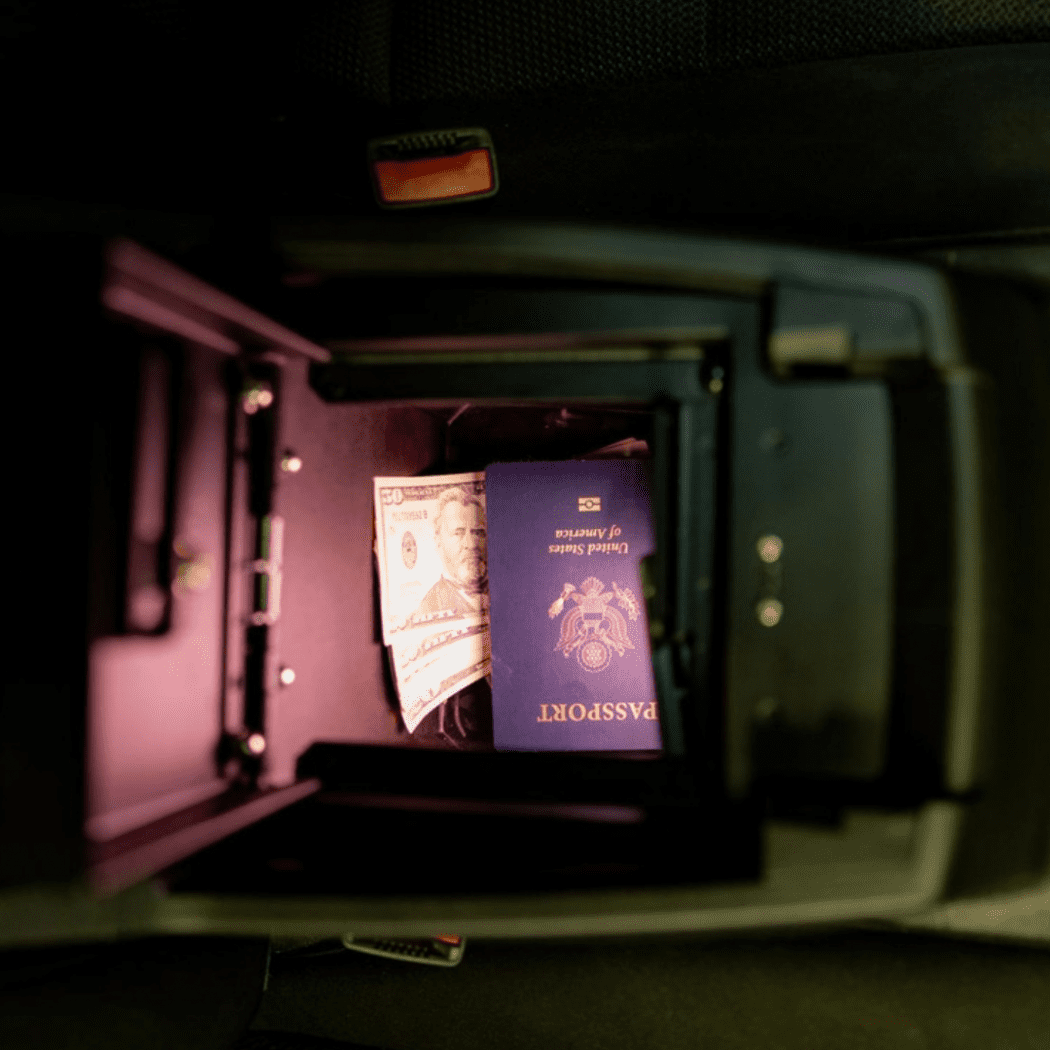 Open Tuffy Console Safe inside a 2023+ GMC Canyon or Chevy Colorado center console, showing stored passport and cash for secure, concealed vehicle storage.